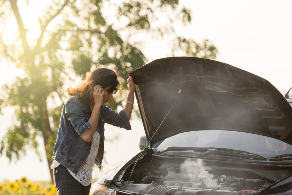 A woman checking on her engine on the side of the road after it overheated. Dann's Discount Auto Sales Visalia, CA