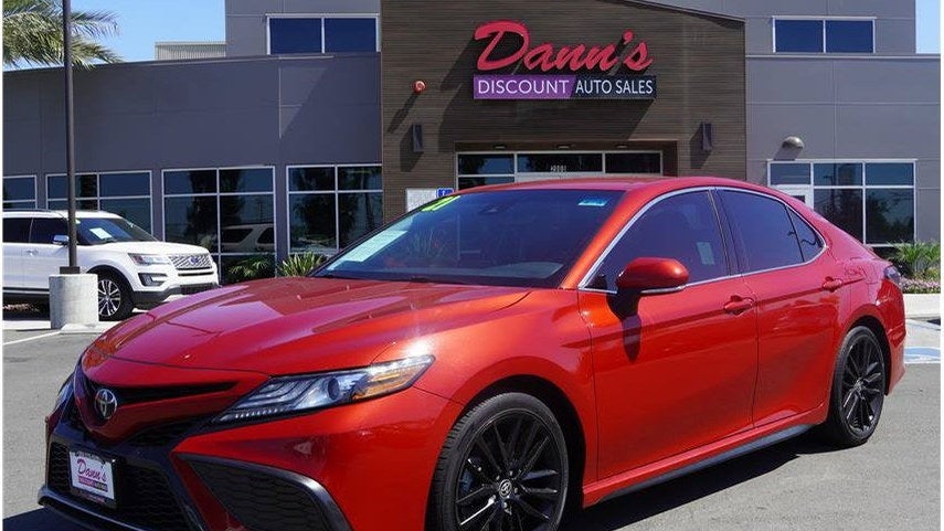 Red used Toyota Camry for sale in front of the Dann's Discount Auto Sales showroom