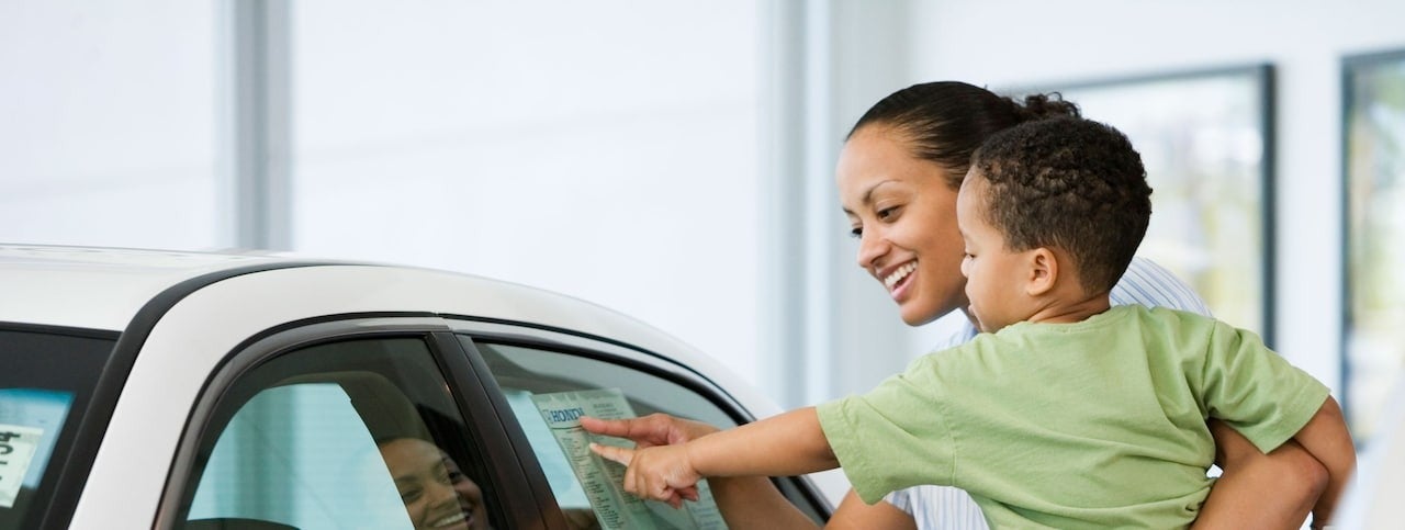 image of a woman holding a child pointing at a car